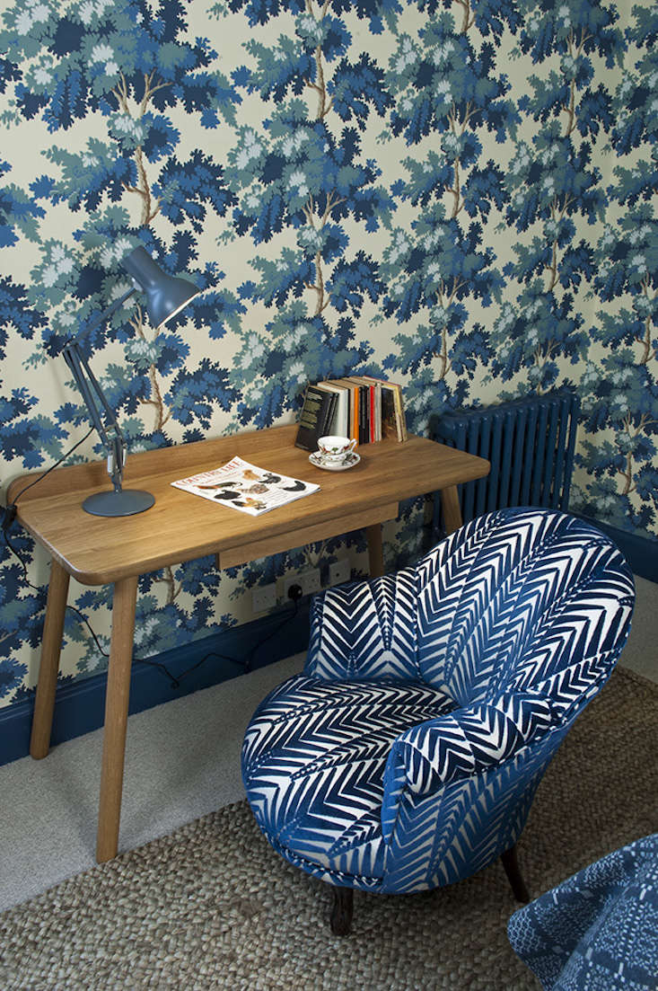 A radiator and baseboard painted in deep blue to match the wallpaper background.