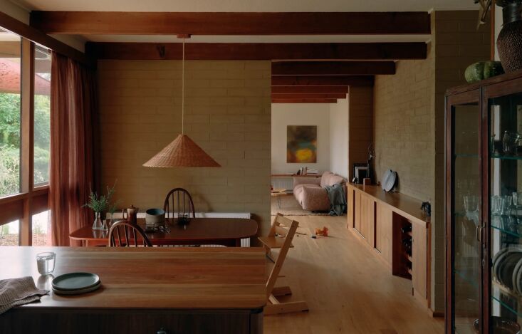 Modern open-plan kitchen and dining area with blackbutt wood floors and earthy color tones.