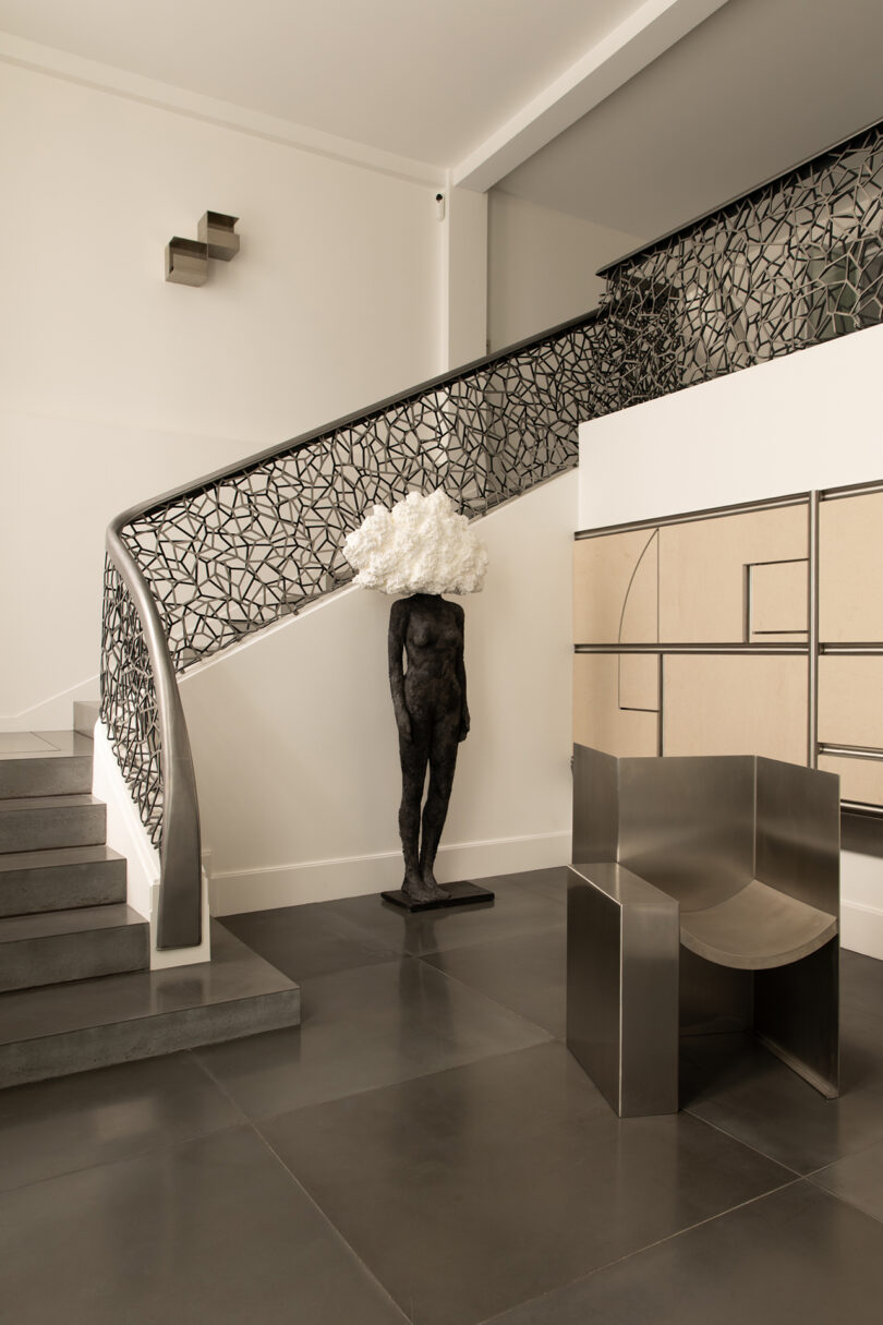 A sculptural metallic staircase and minimalist furniture in a modern Parisian apartment.