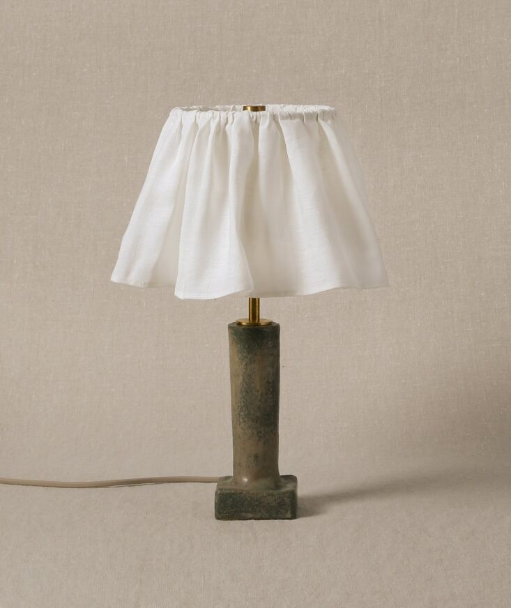 A ceramic lamp base designed to look like a folded curtain or draped fabric.