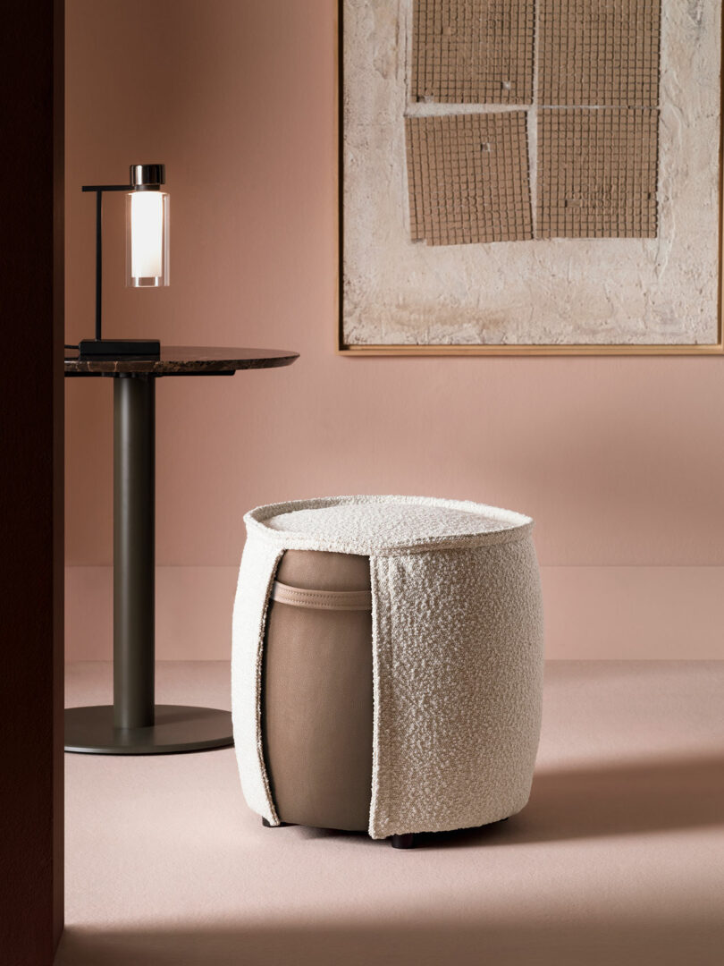 Detailed view of a textured cylindrical ottoman with a white fabric overlay against a minimalist backdrop.