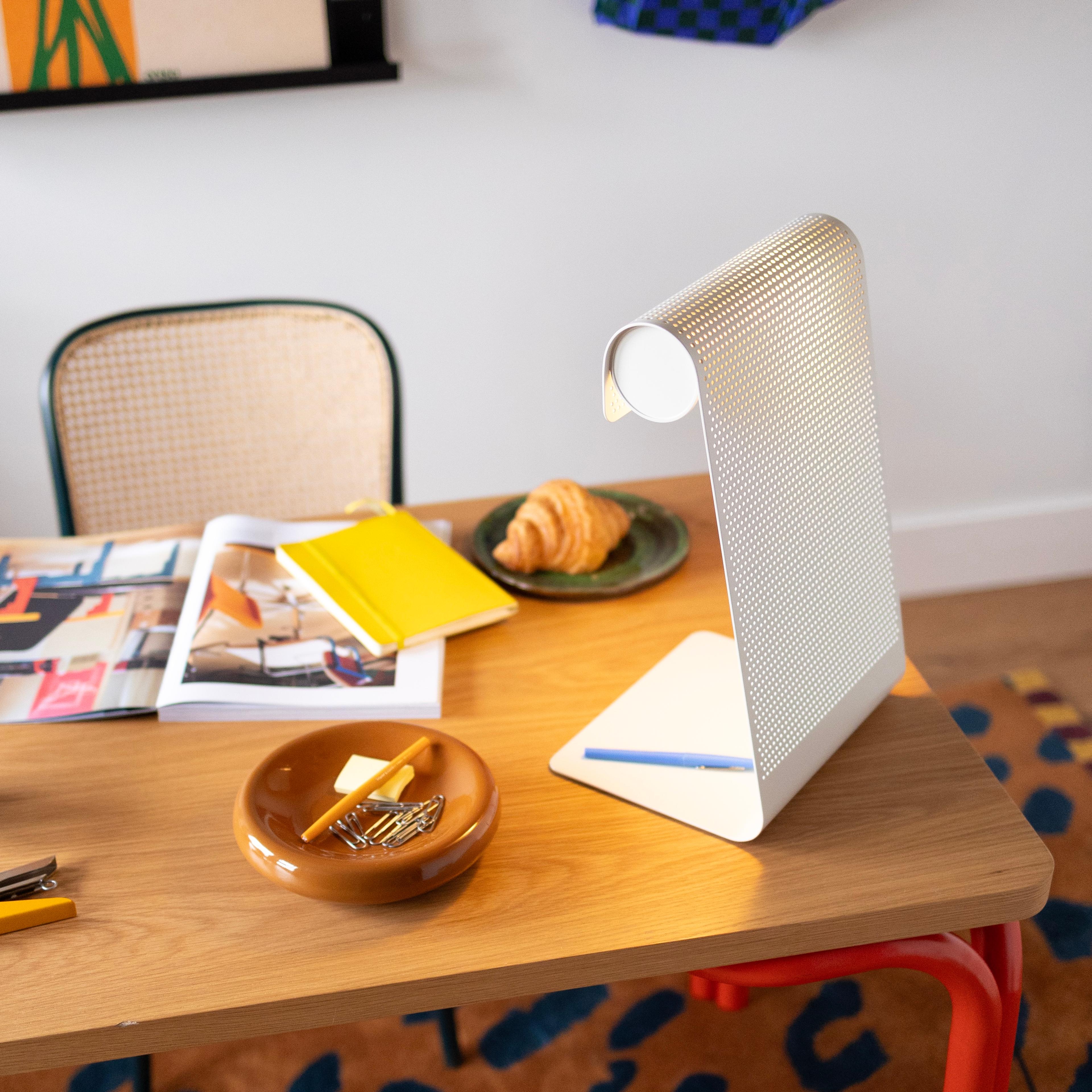 A vintage schoolhouse-style desk lamp providing targeted illumination on a workspace.