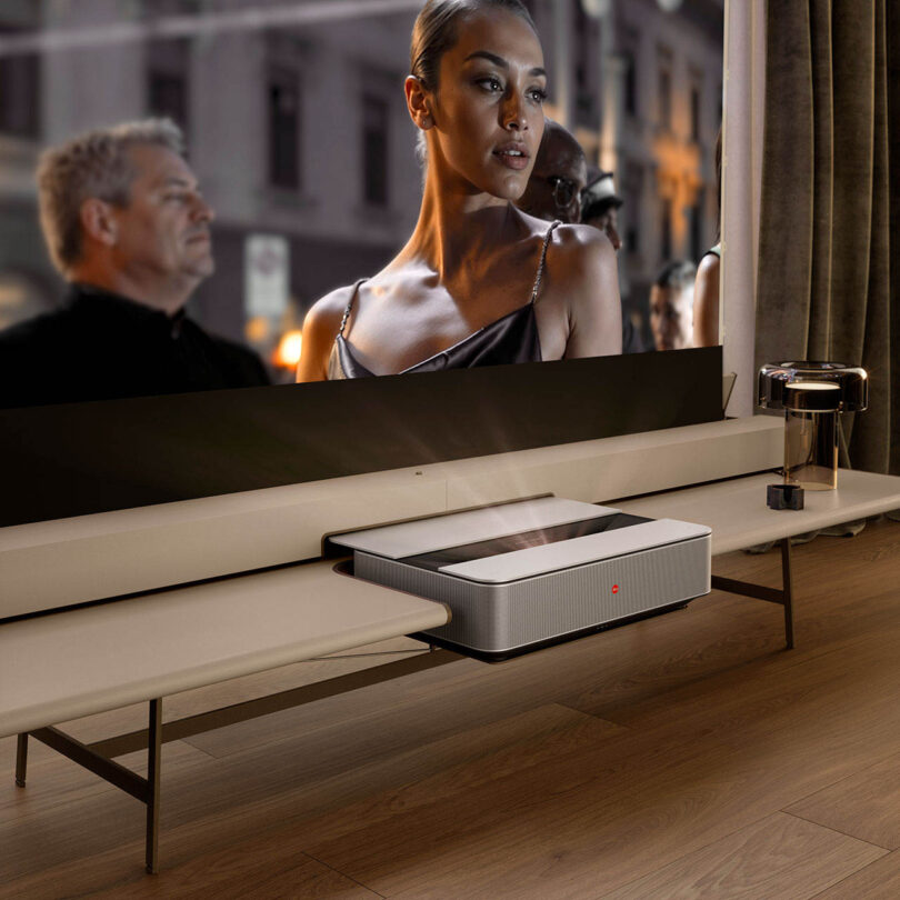 A large projector screen displaying a high-definition movie scene in a brightly lit modern living room.