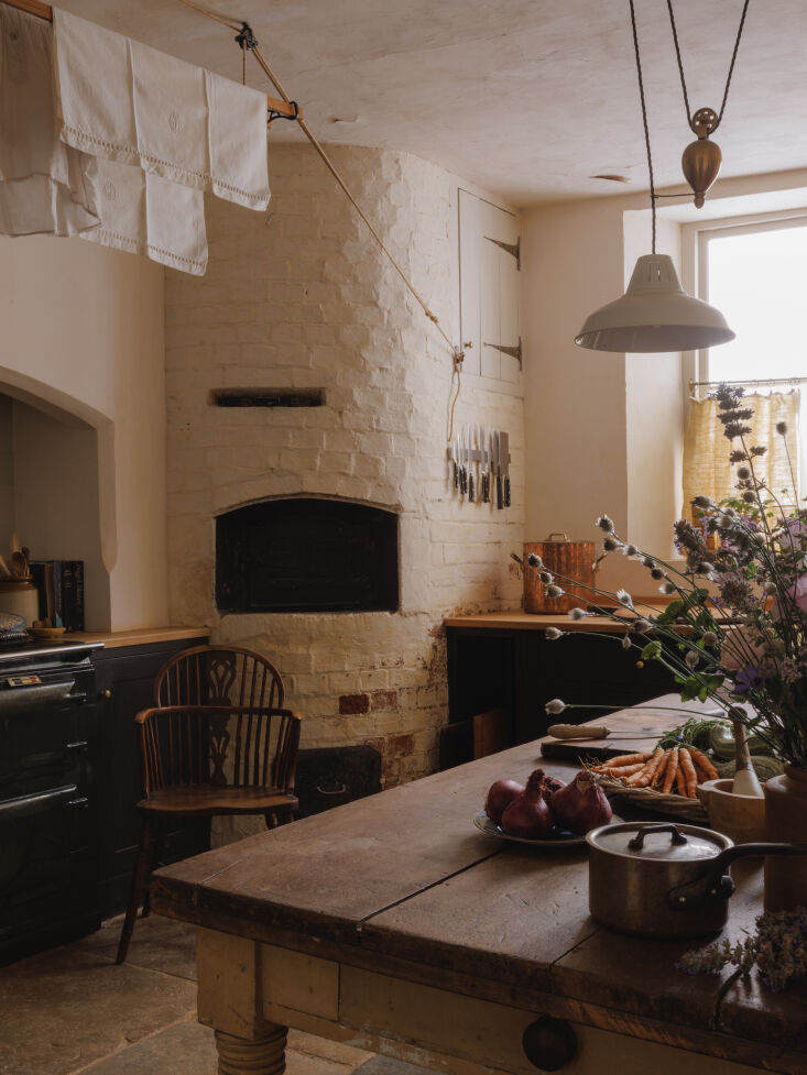 A restored kitchen featuring a traditional AGA range, a historic bread oven, and Plain English cabinetry.