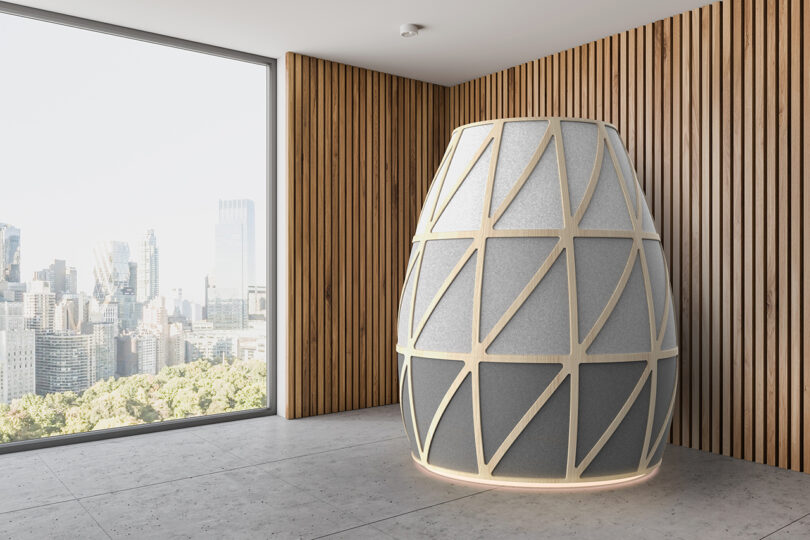 The geometric Iris Pod structure situated in a large modern office with wooden walls and large windows.