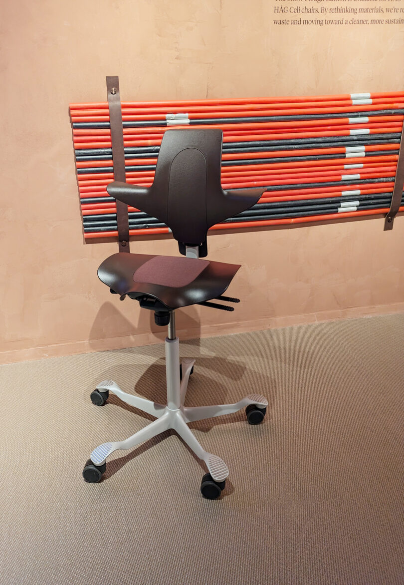 A sleek black ergonomic office chair showcased against a modern backdrop at a design exhibition.