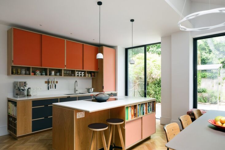 A colorful kitchen featuring a coral pink palette with various integrated storage units and shelves.