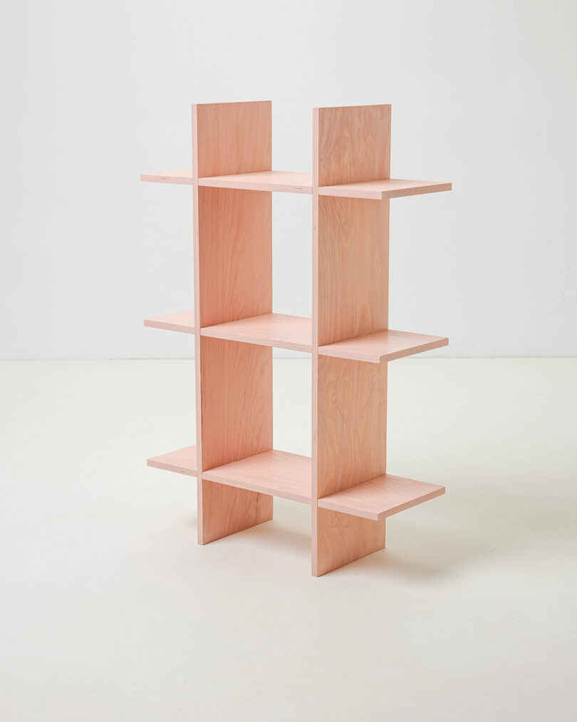 A light-colored three-level wooden shelf with an open grid design.