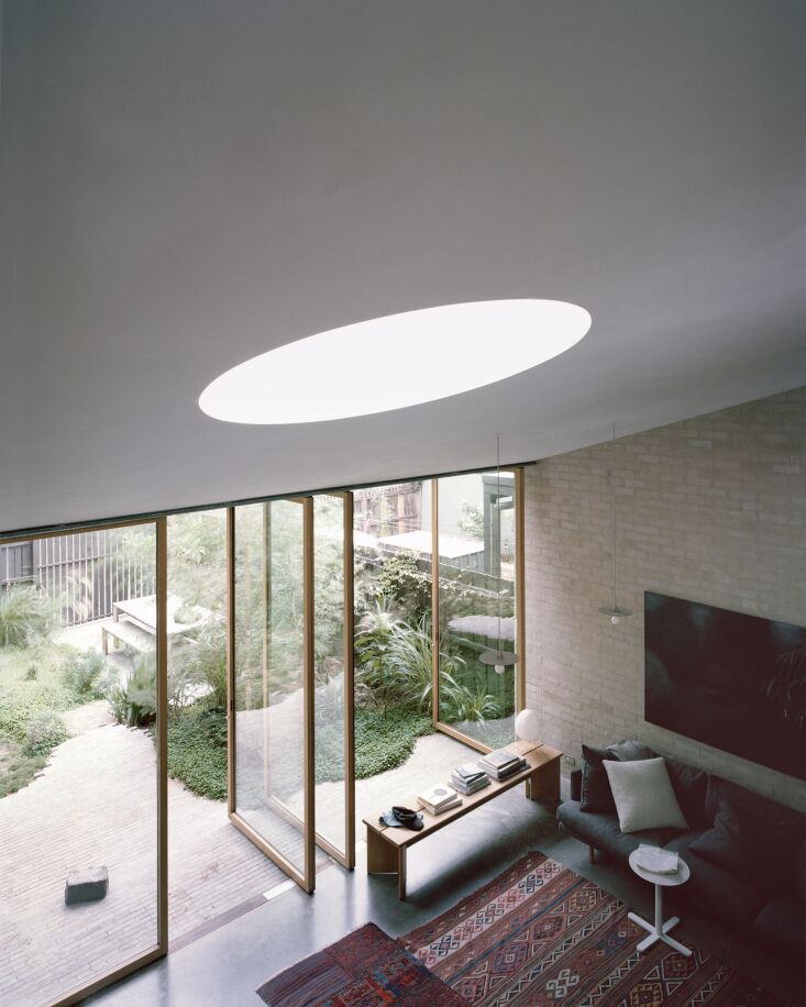A circular skylight in a white ceiling casting a dramatic beam of light into the room.