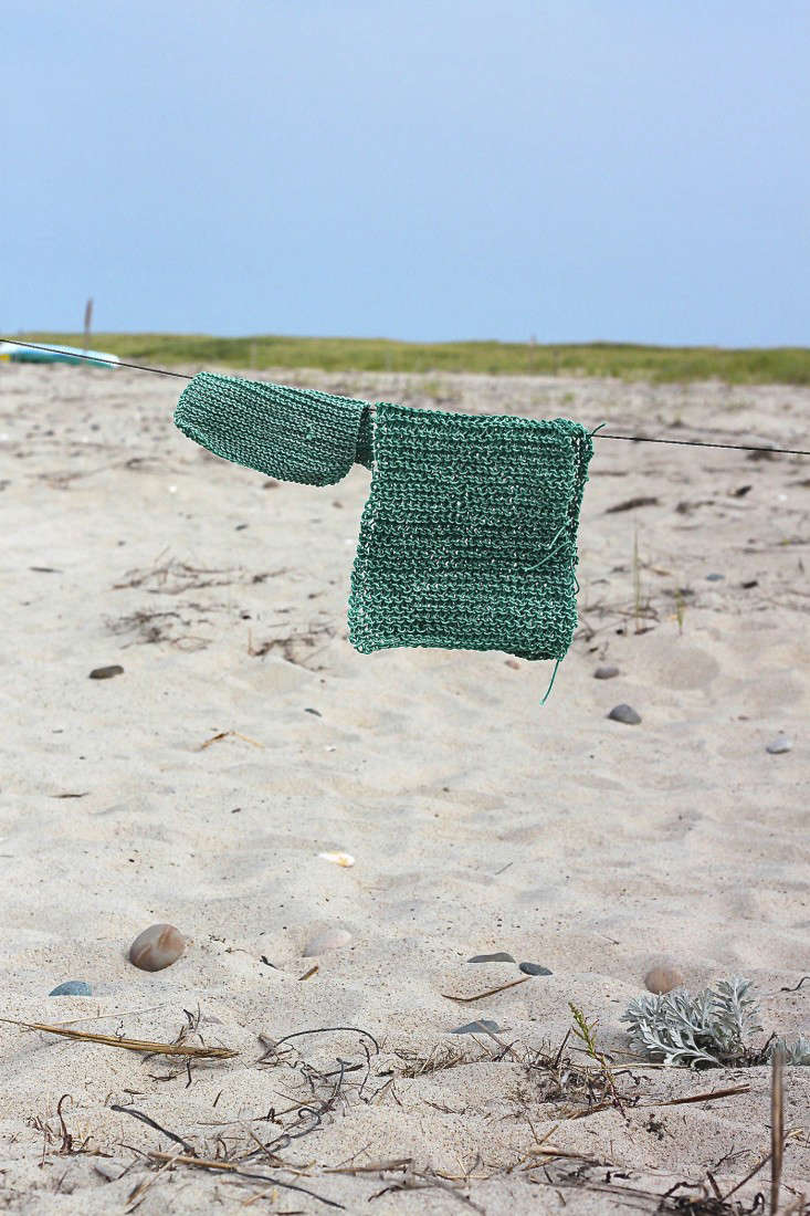 Mariner's green knit mats hanging outdoors against a beach backdrop.