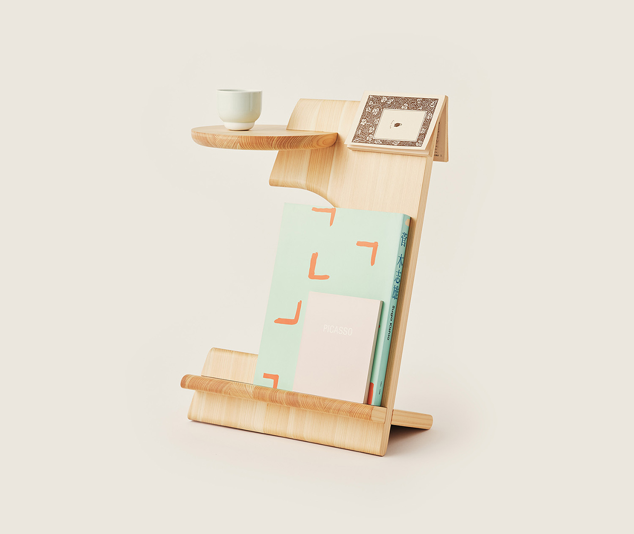 The Bookmarker table holding a white coffee mug on top and books stored in the lower ligament ledge.