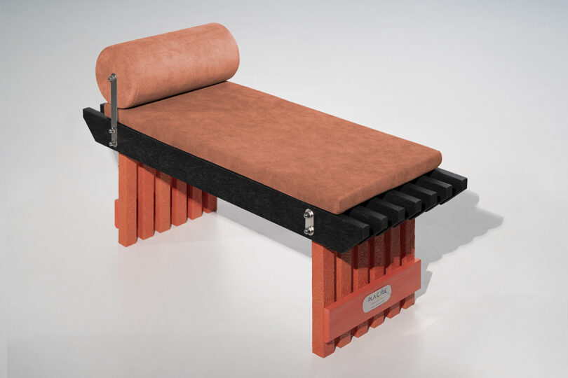 A Torii bench featuring orange supports and a rust-colored upholstered cushion.