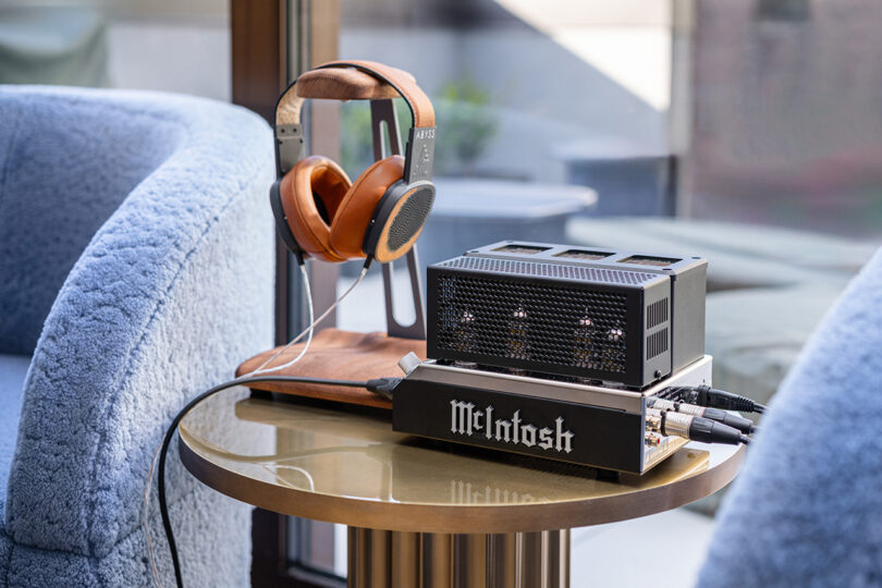 Luxury headphones on a wooden stand next to a McIntosh amplifier.