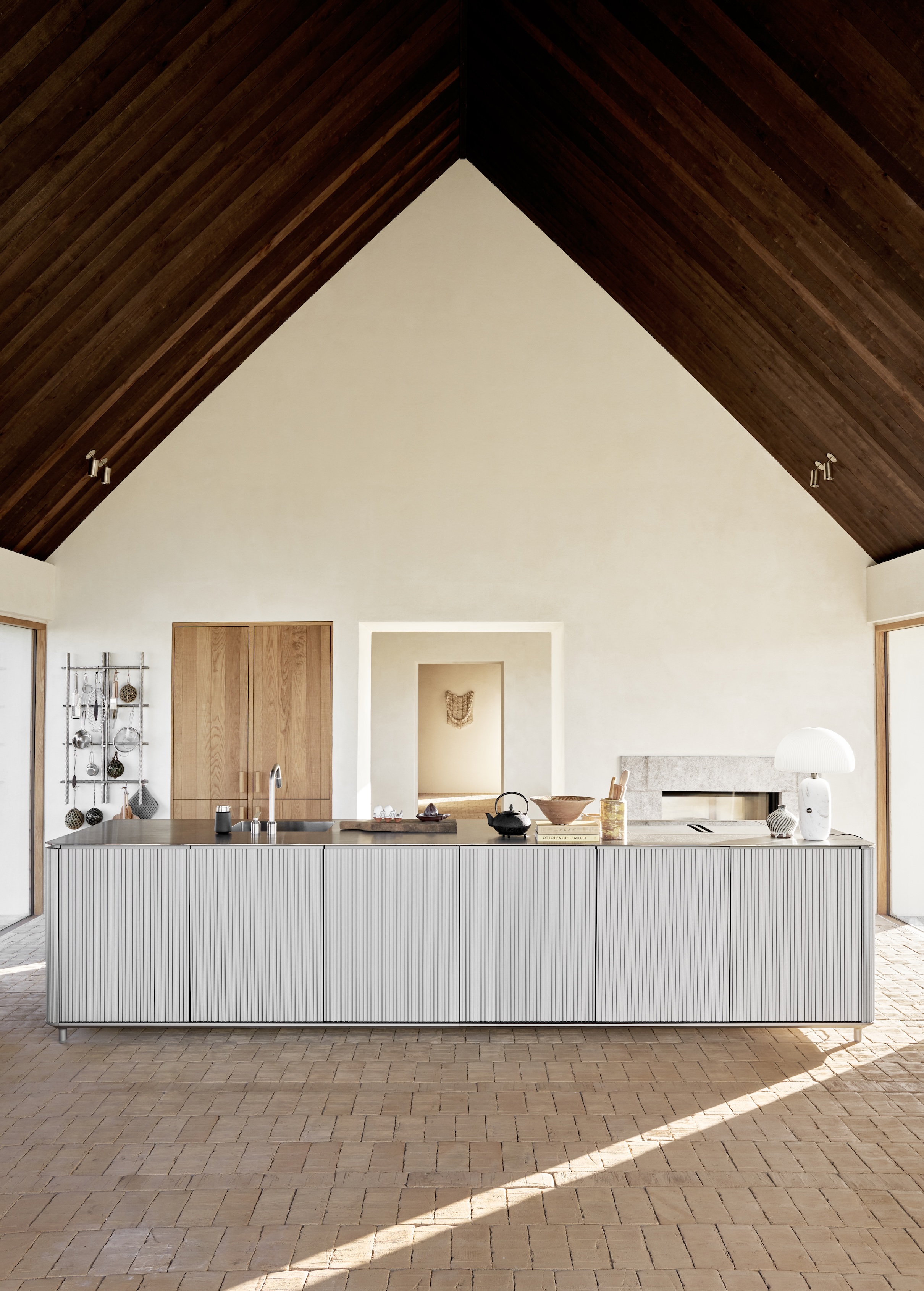 The Vipp V3 kitchen island in reeded aluminum on a floor made of sand-laid bricks.