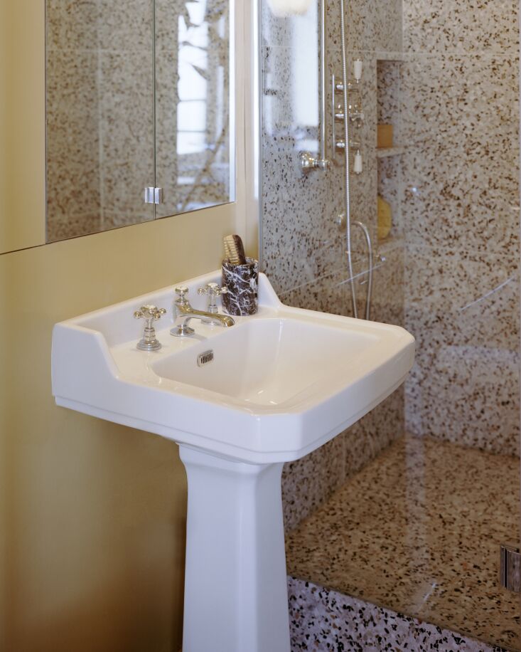 A compact bathroom with bright yellow walls and a traditional white pedestal sink.