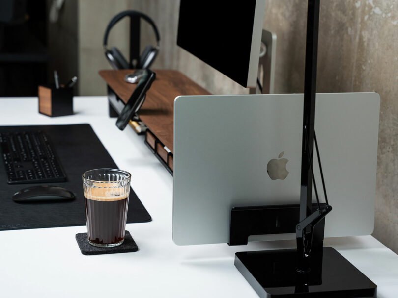 A Balolo vertical laptop stand holding a MacBook beside a main monitor on the setup cockpit.