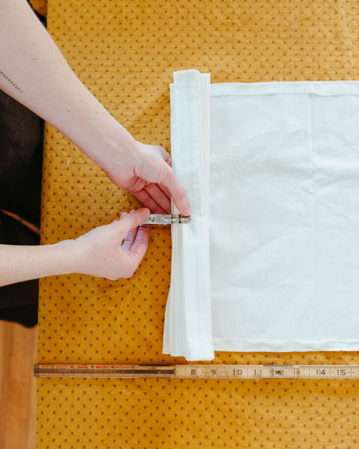 Close-up of hands accordion-folding fabric into even one-inch pleats.
