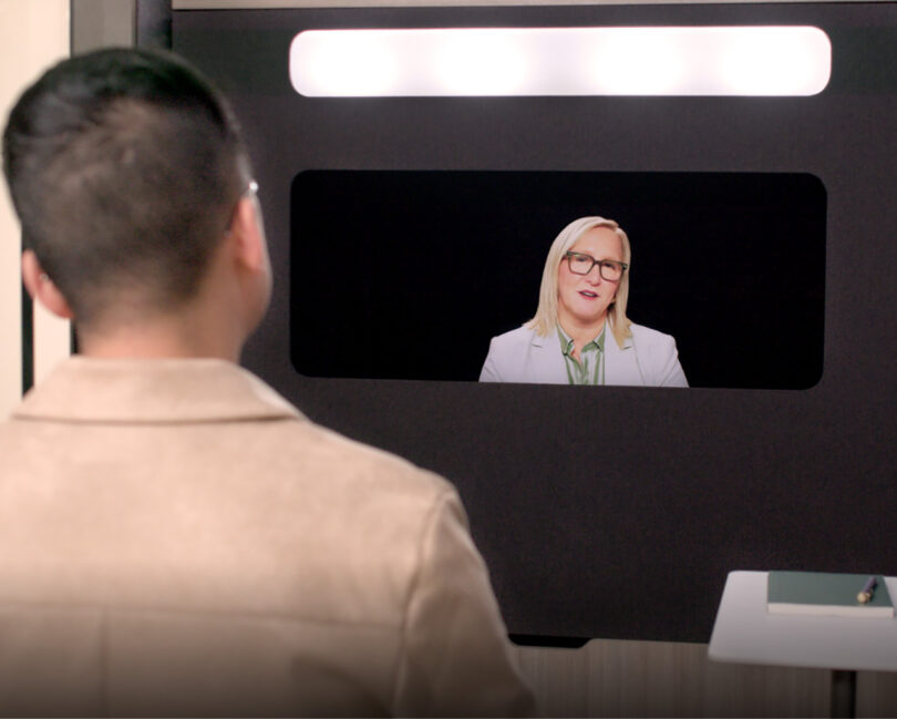 A woman with glasses appears on the Ocular View screen speaking to a participant in the pod, highlighting the clarity of the connection.
