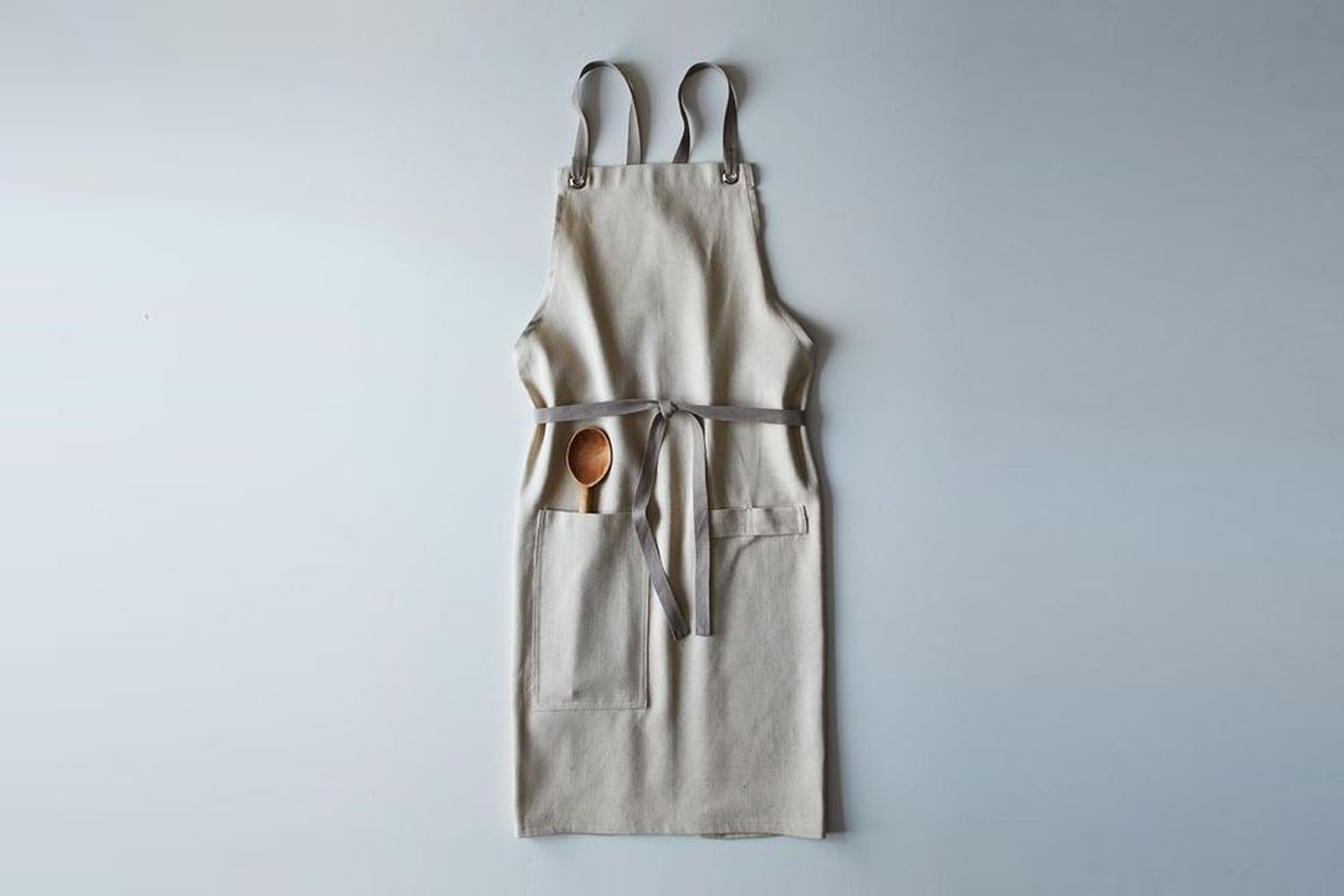 A person wearing a cross-back linen apron showing the strap configuration.