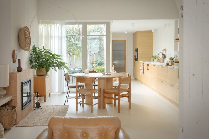 A traditional Dutch living room with a wood-burning stove, stained glass windows, and historic architectural details.