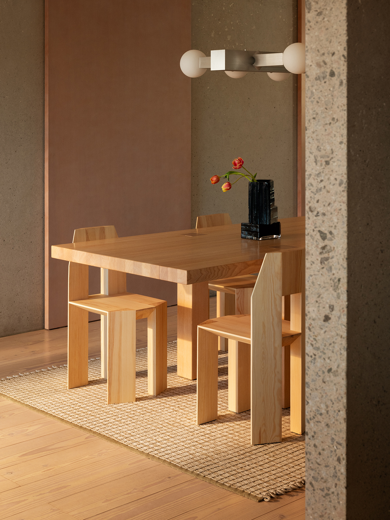 A minimalist dining area featuring a group of Min Chairs around a matching solid wood table.