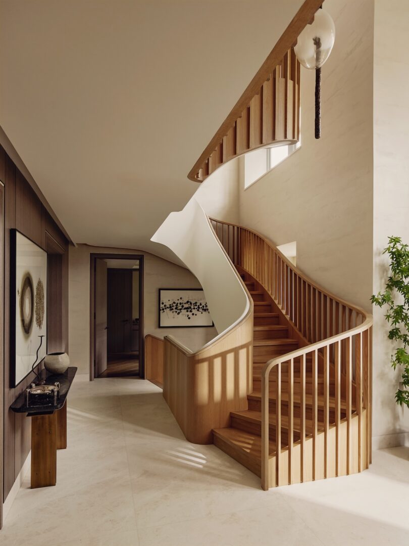A curved wooden staircase with vertical railings in a modern, brightly lit interior.