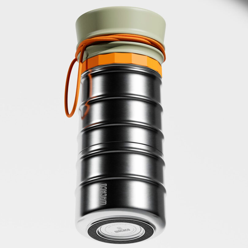 A metallic, ribbed insulated bottle with a beige cap and orange strap against a clean white background.