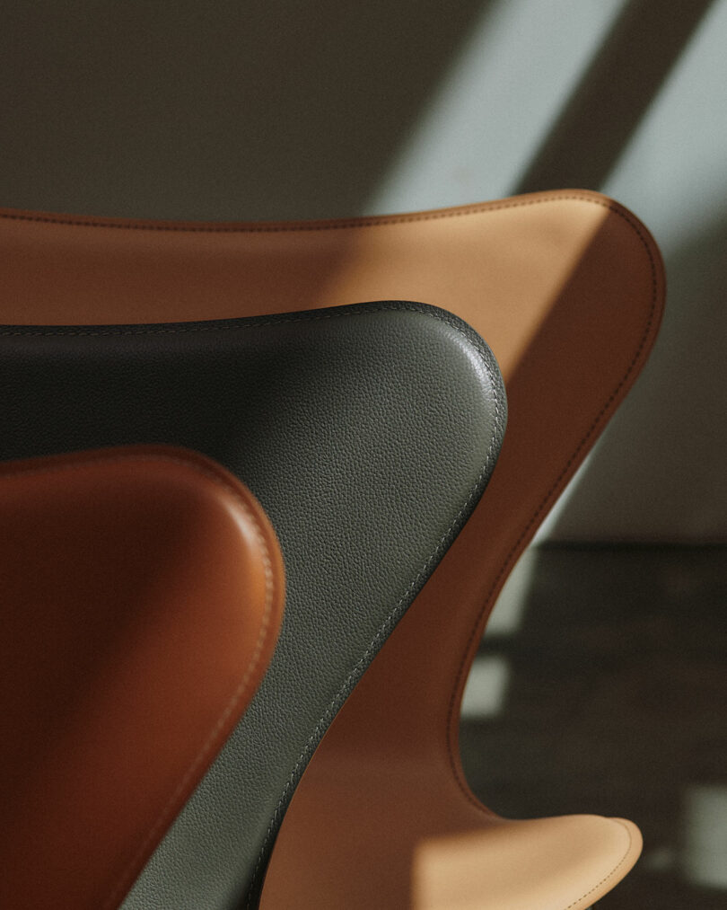 Three Series 7 chairs in black, tan, and dark brown leather layered together to show the color variety.