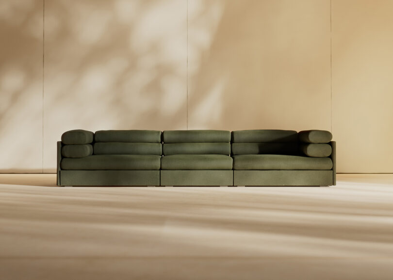 An olive green modular Elogio sofa centered in a sunlit, beige minimalist room.