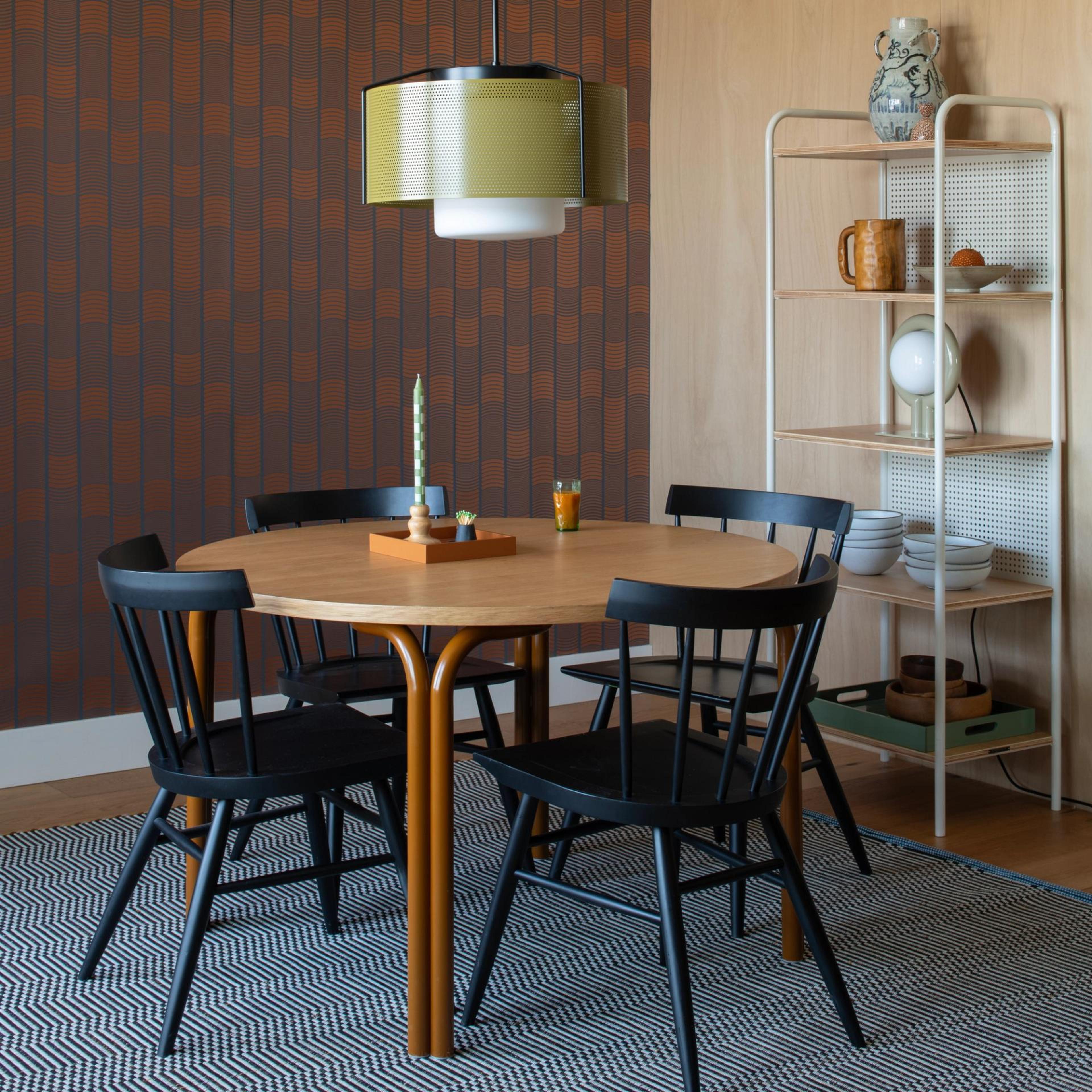 A tall, minimalist taper candle standing on a dining table.