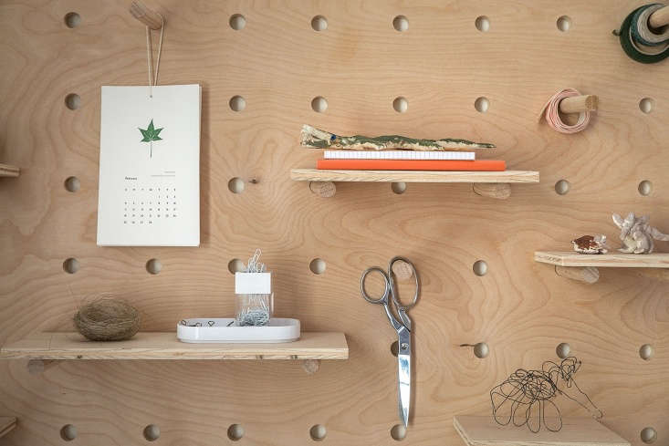 A wooden pegboard displaying small sculptures and creative art pieces.