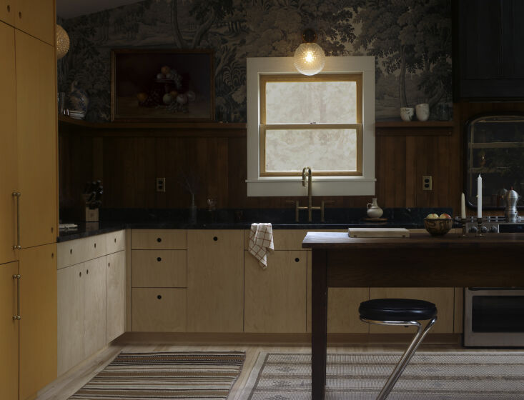 The kitchen illuminated at night by soft incandescent globe sconces, creating a moody atmosphere.
