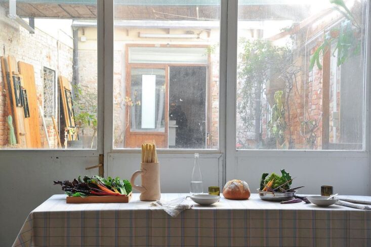 A collection of fine Italian linens displayed within a rustic, traditional artisan studio setting in Italy.