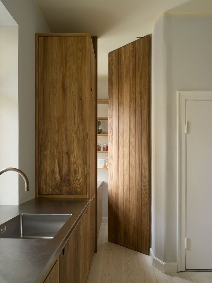 A floor-to-ceiling wooden pantry door with pinion hinges that create a floating appearance.