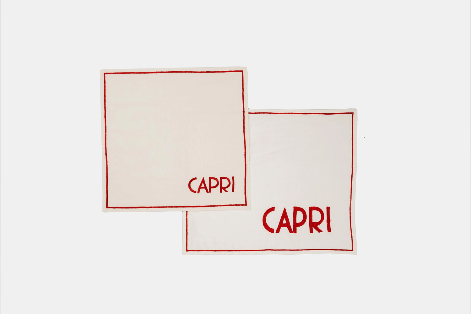 Embroidered napkins with destination names like Capri and St. Moritz in a classic Parisian font.