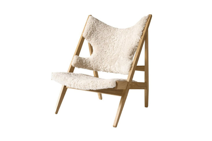 Audo Copenhagen Knitting Chair in oak with sheepskin upholstery showing the triangular side profile and arm cut-outs.