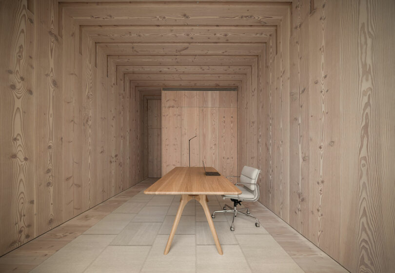 A minimalist office corner showing the uniform texture of light-colored Douglas Fir wood on the walls and ceiling.