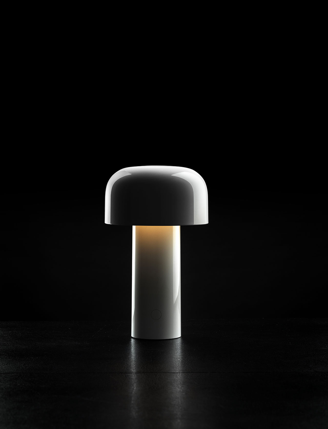 A modern white mushroom-shaped lamp emitting a soft, warm amber glow against a dark background.