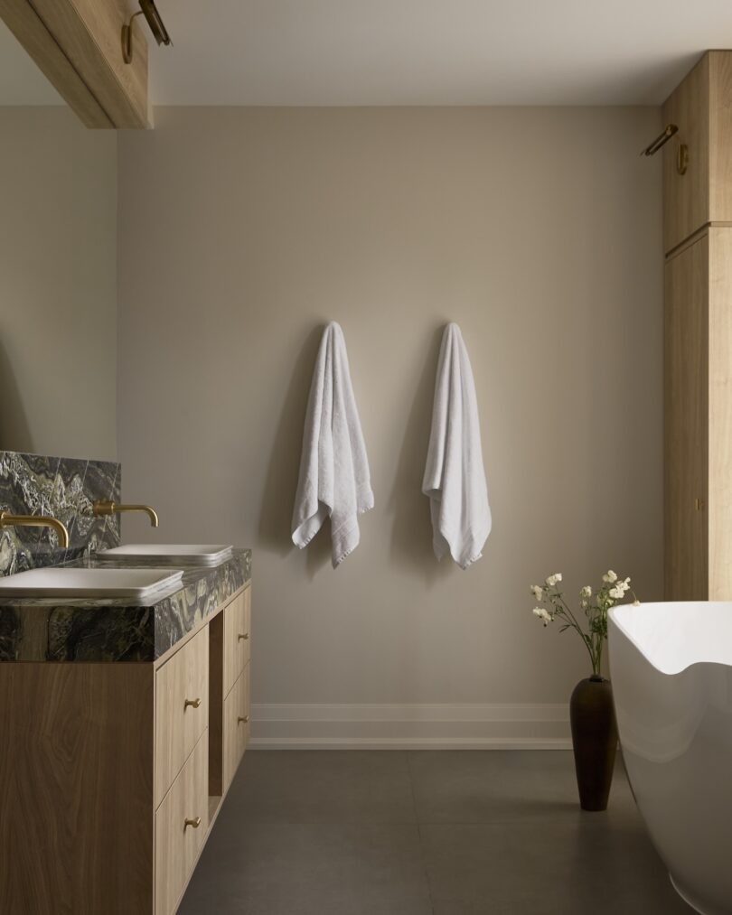 Minimalist bathroom with wooden vanity, marble counter, and gold fixtures.