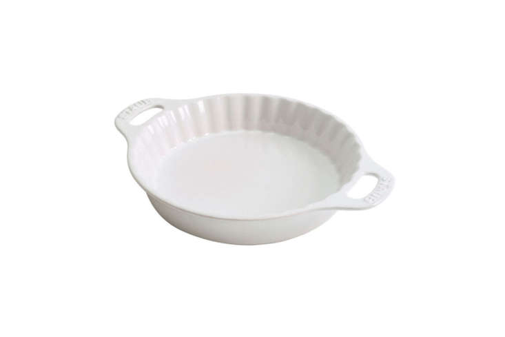A Staub ceramic pie dish in a vibrant cherry red finish.