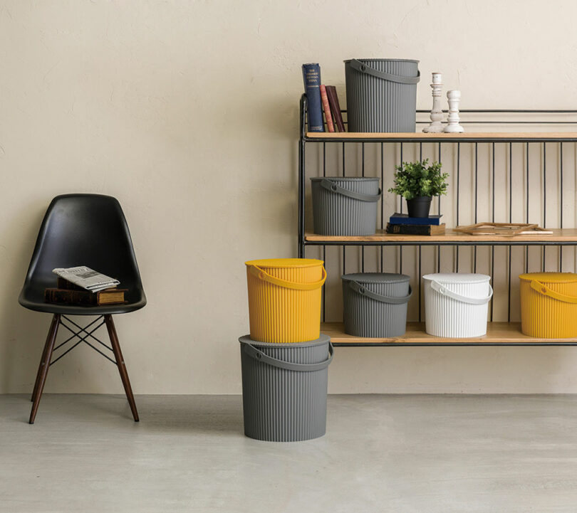A modern living room scene featuring grey and yellow Hachiman Buckets used as decorative storage near a bookshelf.
