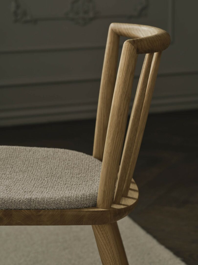 Macro close-up of the solid oak grain and textured beige seat cushion of the Éter Chair.