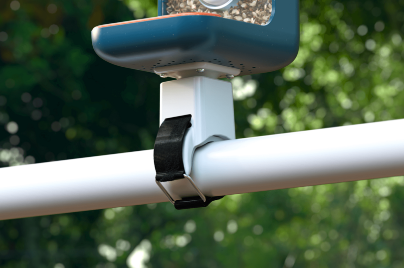 A mounted dark blue Bird Buddy smart bird feeder attached to a wooden post outdoors.