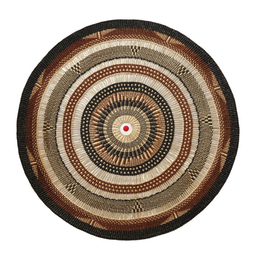 A round woven lamp tapestry featuring concentric circles in earthy tones with a red PET bottle cap at the center.