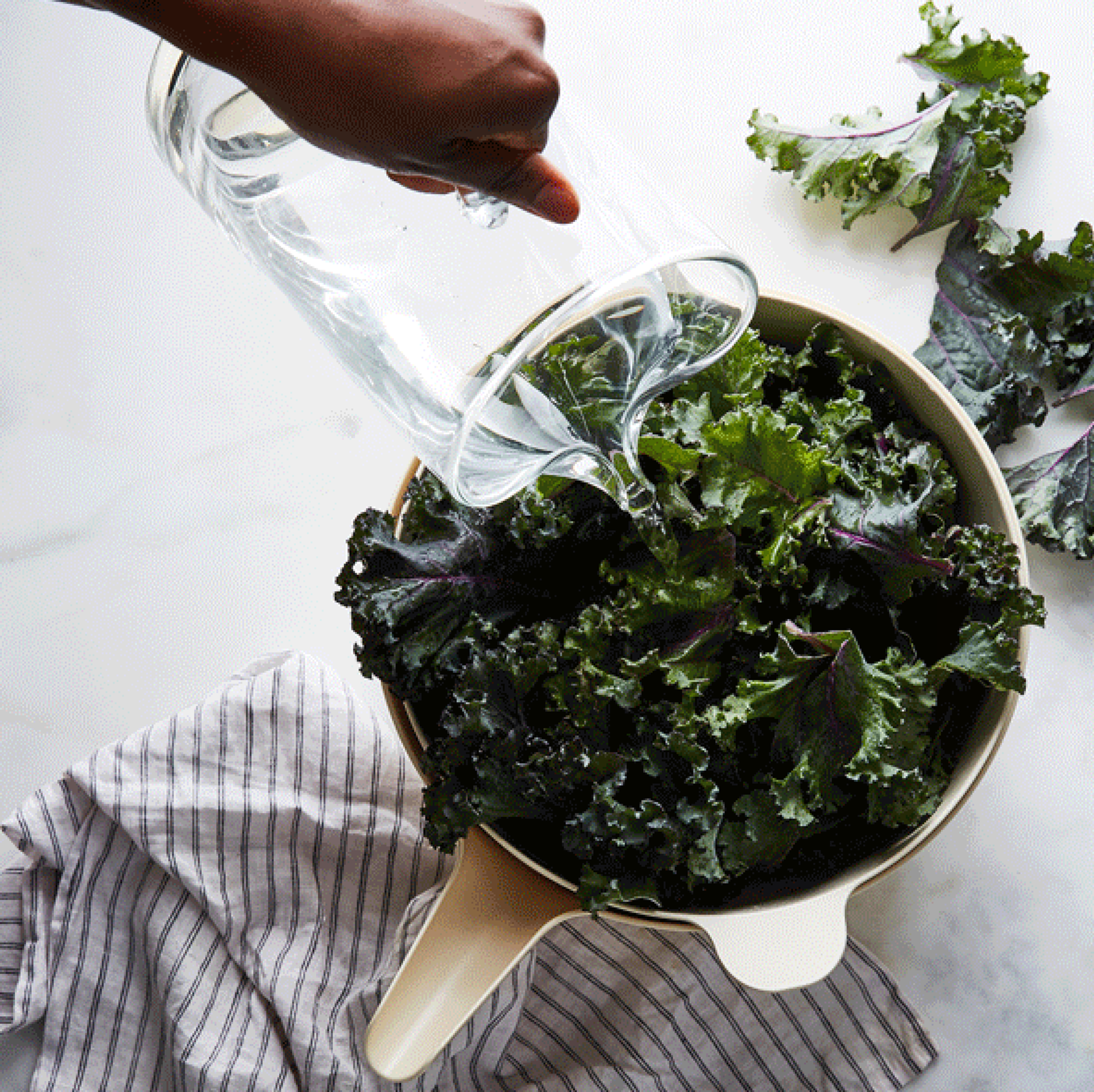 Fresh green lettuce leaves being rinsed and soaked in a simple ceramic bowl of water.