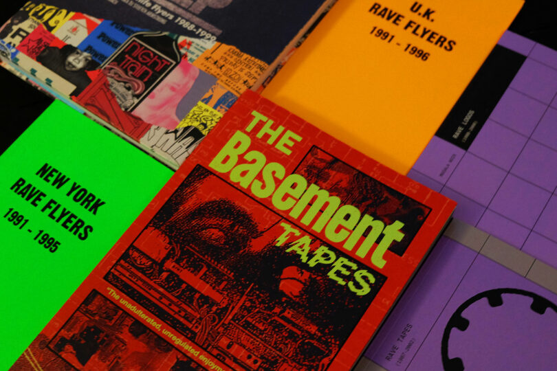 Close-up of rave flyers and booklets like 'New York Rave Flyers' on a table.