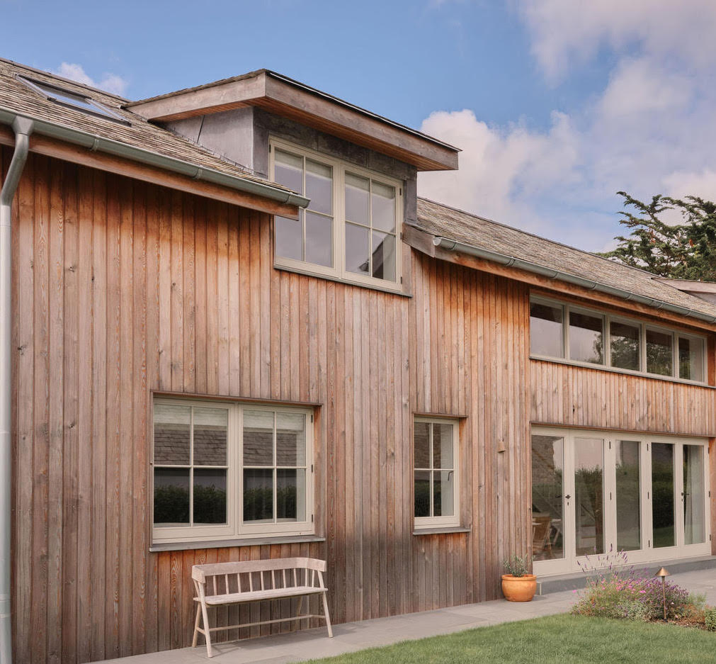 Detail of larch wood cladding on a house exterior next to a large vertical window.