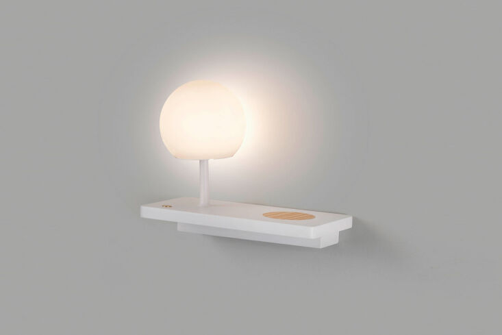 A black wall shelf featuring a white globe light and a built-in wireless charging pad.