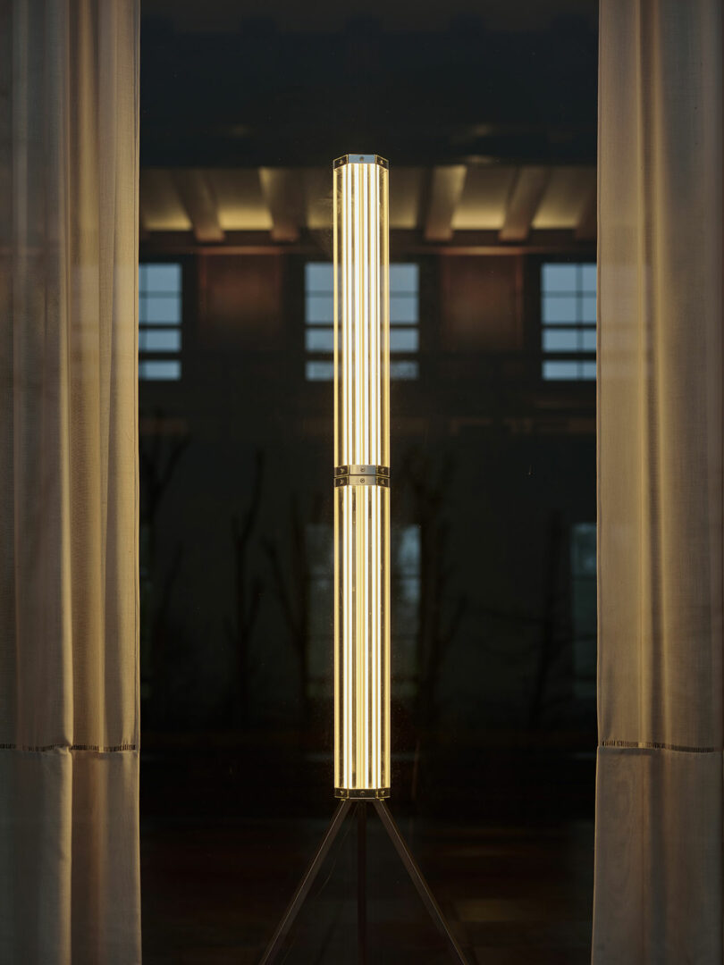 A vertical cylindrical SuperWire floor lamp with multiple LED strips emitting warm light.
