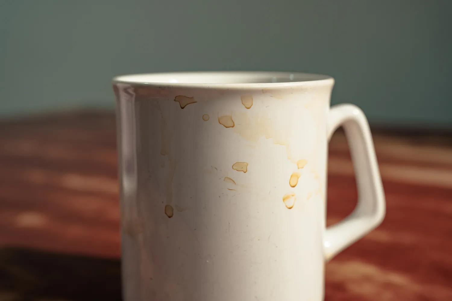 Close-up of a white ceramic mug with dark coffee or tea stains on the interior.